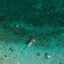 Aerial view of clear waters off the coast of Sivota, Greece with swimmers in the water.