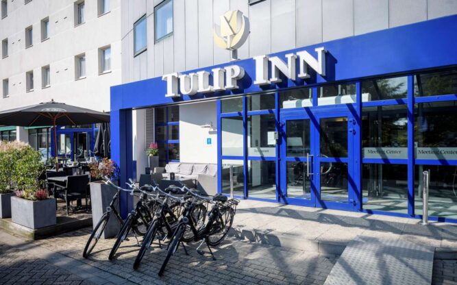 The blue front entrance to the Tulip Inn Hotel in Antwerp with bicycles parked out front