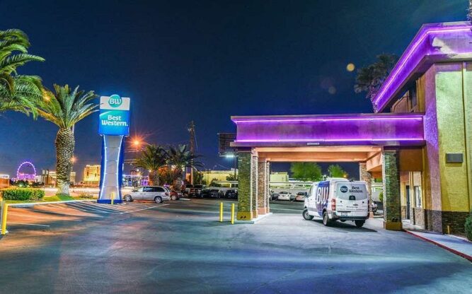 The entrance to the Best Western McCarran Inn Las Vegas Airport Hotel at night with a white van parked out front.