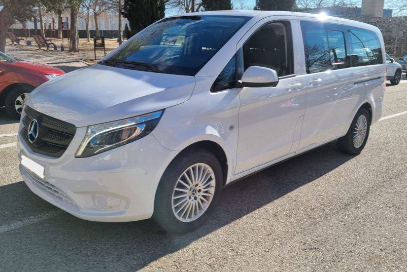 Taxi Madrid Airport (Minibus) - Welcome Pickups Side view of a white Madrid Airport taxi minibus, parked outside.