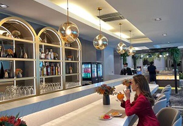 A lady in a red suit drinking at the bar of the Miracle Transit Hotel in Bangkok Airport