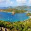 An aerial view of Sint Maarten overlooking a bay filled with sail boats surrounded by lush greenery.