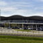 The front view of the Split Airport Terminal with a a road running along in front of it next to a grassy area.