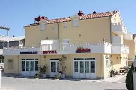 A small pale yellow building with white windows and balconettes, and a terracotta roof