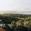 View of Lloret de Mar, showing hills with trees and houses, and a body of water in the distance.