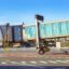 a gate walkway attached to an airport hangs over the runway awaiting the next plane