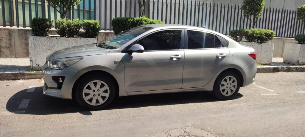 A silver Cancun Airport taxi sedan parked on the side of a sunny street, featuring four doors, tinted windows, and compact styling; commonly used for private airport transfers from Cancun Airport.