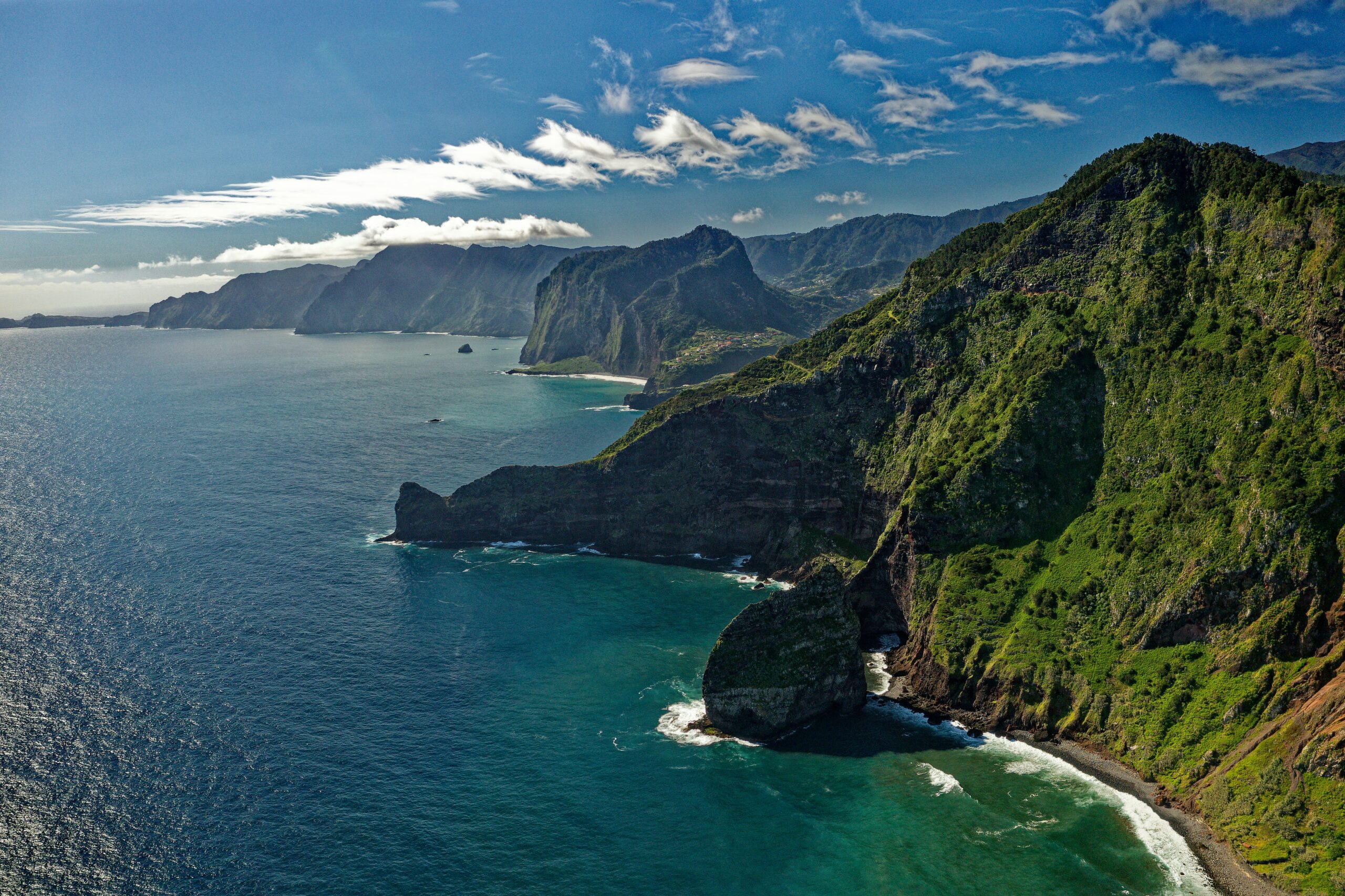 A green and luscious mountain meeting a vast and blue ocean.