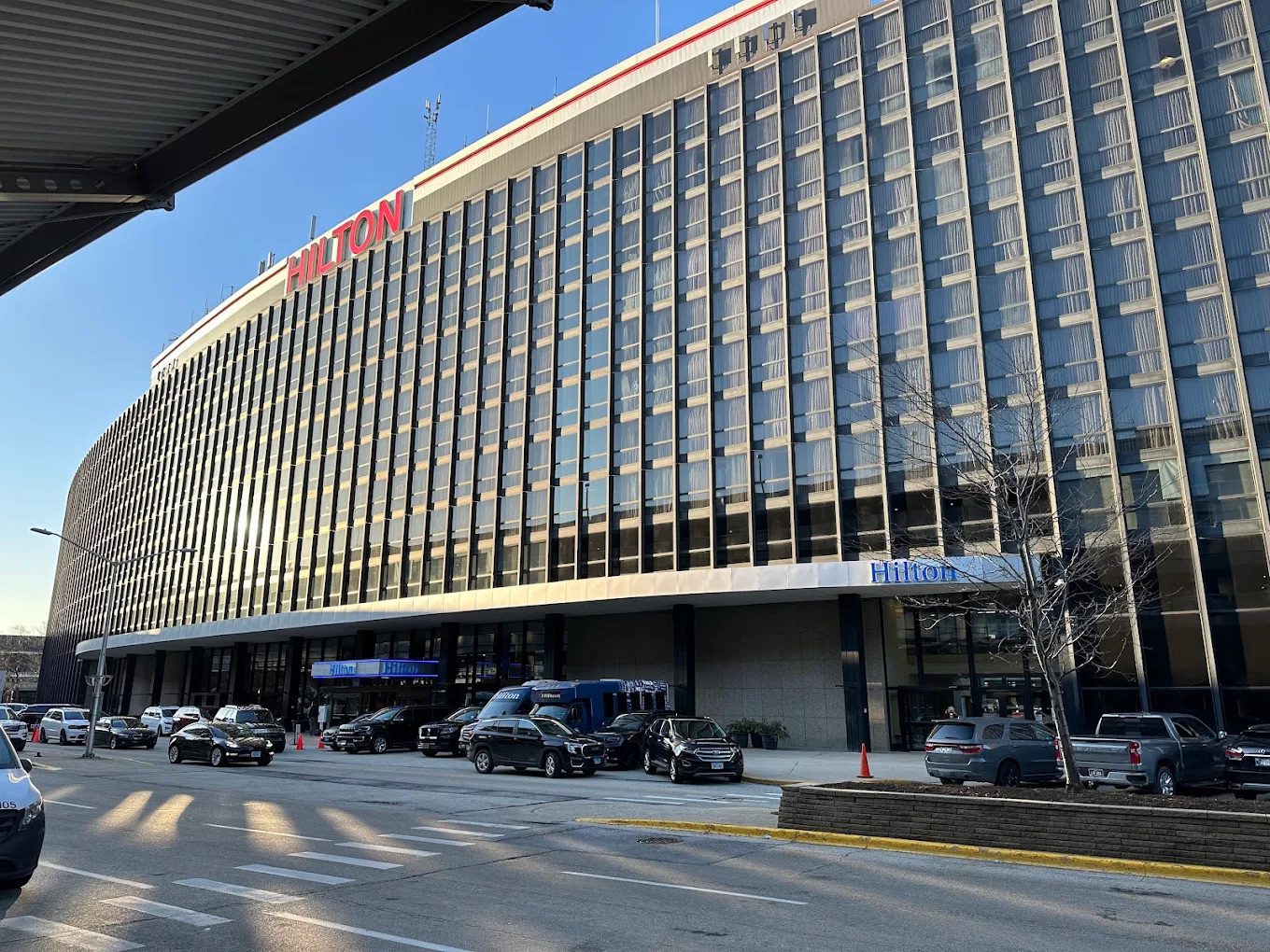 The tall and slightly curved Hilton Hotel at Chicago Airport with a red sign on top of the building.