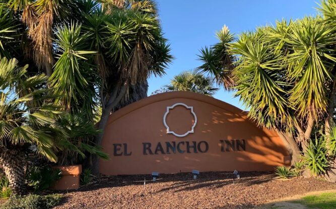 The El Rancho Inn sign surrounded by palm trees