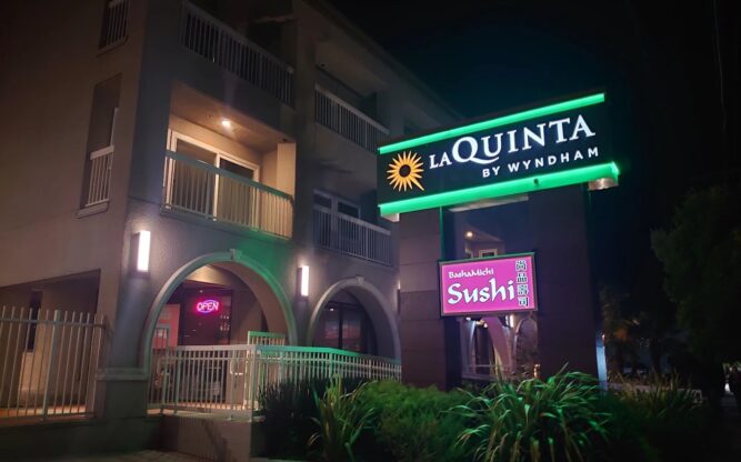 The entrance to the La Quinta by Wyndham Hotel near SFO lit up at night with a neon sign.