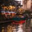 A boat sailing down the canal in San Antonio at night with restaurants on the bank lit up